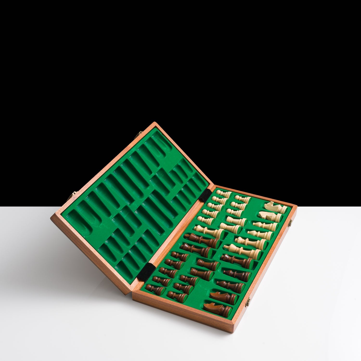 Chess pieces in a wooden box with green felt interior on a white background