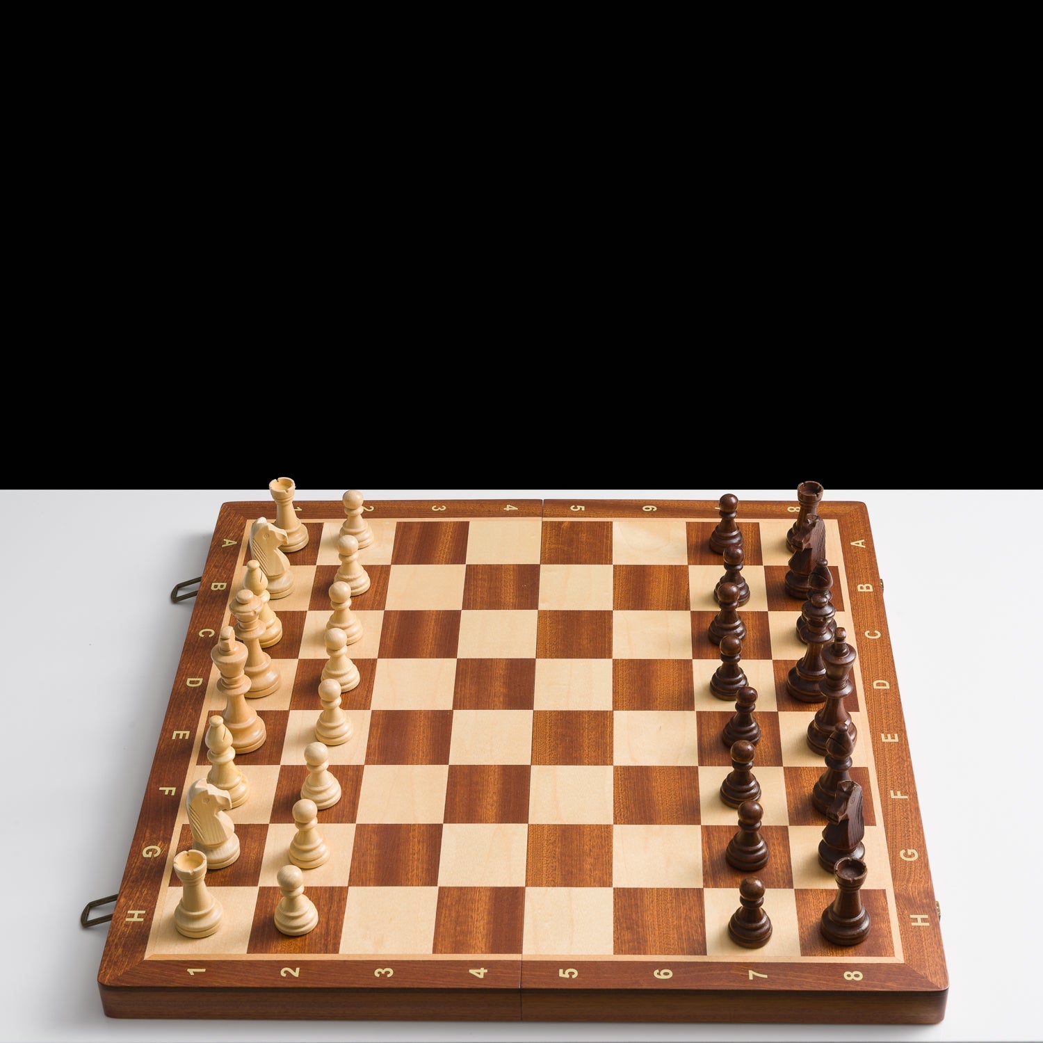 Wooden chessboard with pieces on a white background